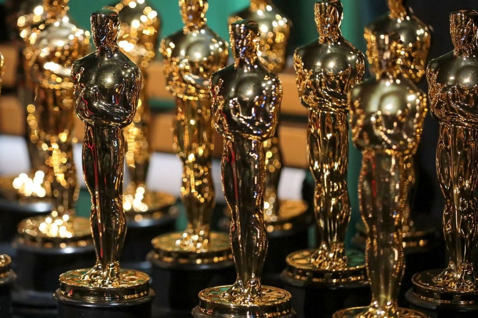 Rows of gold Oscar statuettes lined up on a table