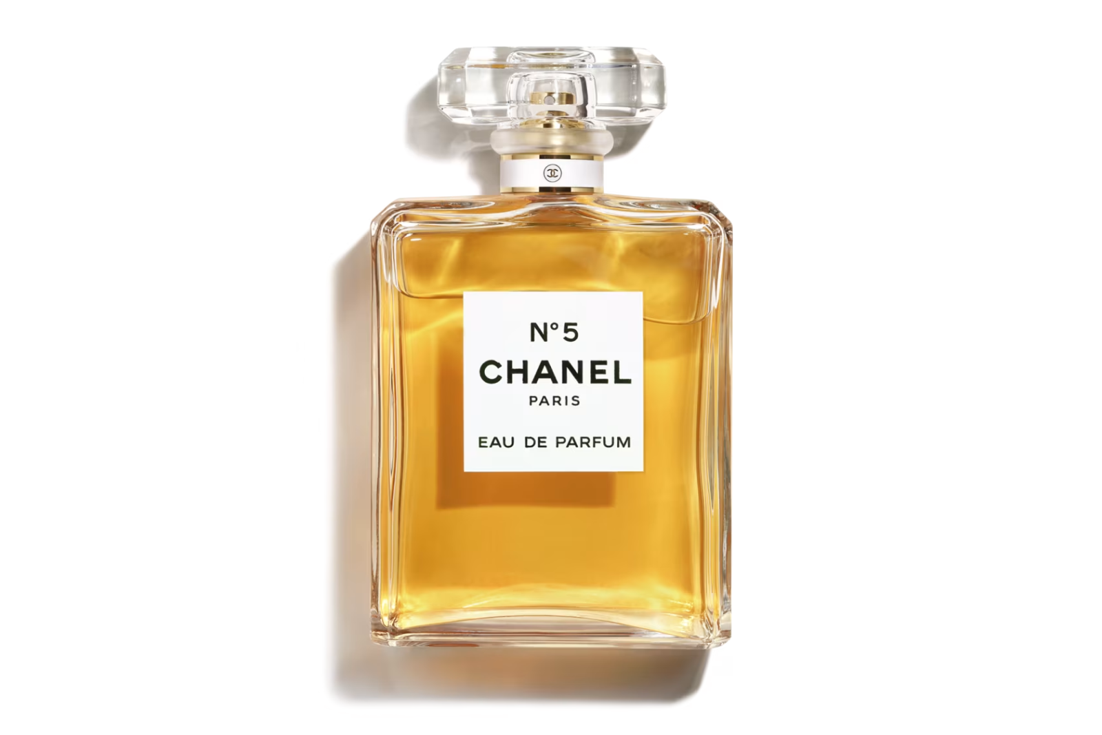 A bottle of Chanel No. 5 eau de parfum filled with golden perfume, on a white background
